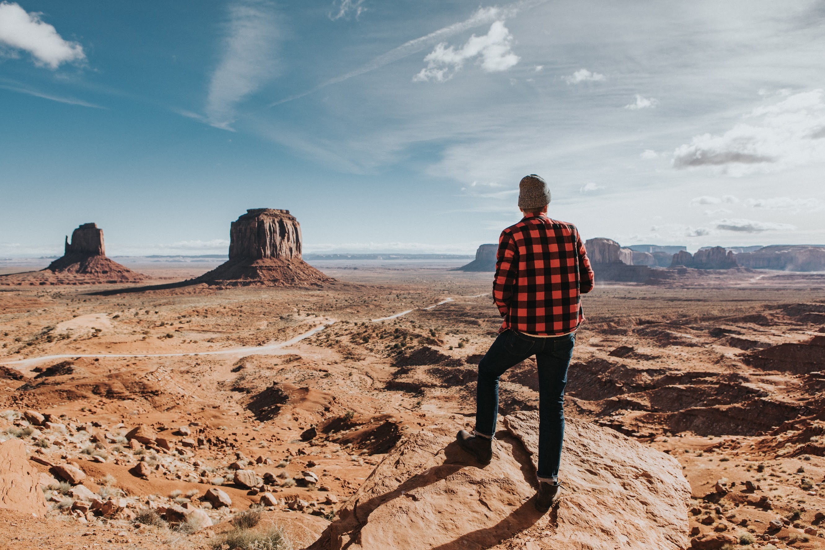 landing image of a person standing on the edge of a cliff looking at buttes